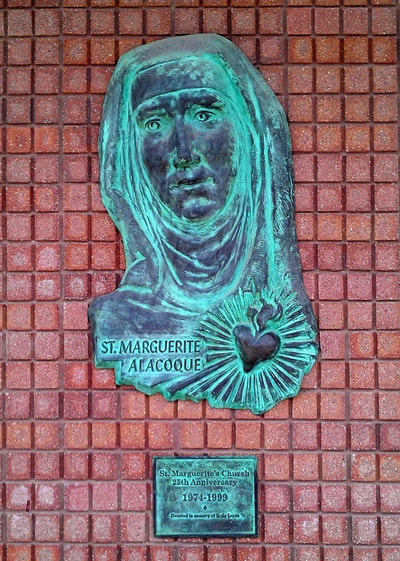 A patinaed sculpture of Saint Marguerite Alacoque located by the entrance.